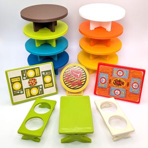 May include: A collection of colorful toy tables and serving pieces. The tables are round and square, in shades of brown, white, green, blue, orange, and yellow. Serving pieces include a grill and table settings.
