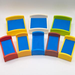 May include: Eight miniature beds in various colors, including yellow, red, white, green, and brown. Each bed has a blue mattress.