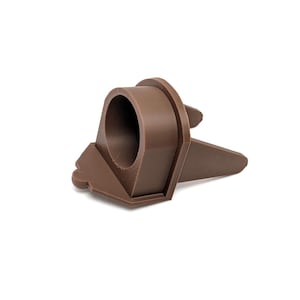 May include: A brown plastic stand with two prongs and a circular opening. The stand is designed to hold a small object, such as a pen or pencil.