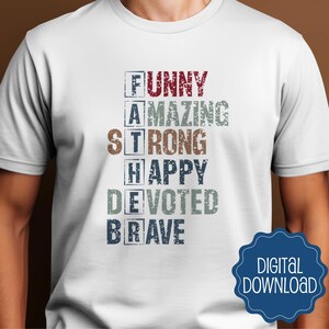 以下が含まれることがあります： さまざまな色とフォントで「FUNNY、AMAZING、STRONG、HAPPY、DEVOTED、BRAVE」という単語を使用して垂直に綴られた「FATHER」という単語が書かれた白いTシャツ。青いデジタルダウンロードバッジが右下にあります。