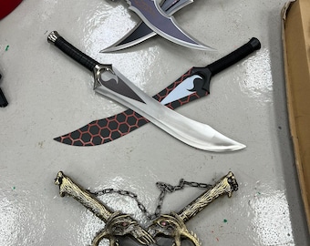 May include: Collection of fantasy swords with various designs. Includes a pair of crossed swords with curved blades and ornate handles, and two other pairs with unique blade shapes and decorative elements. The swords are in shades of silver, black, and gold.