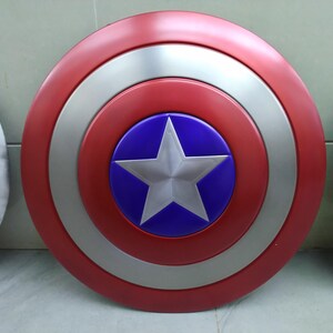 May include: A red, white, and blue Captain America shield with a silver star in the center. The shield is round and has a raised rim.