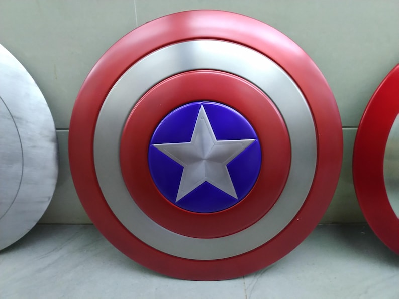 May include: A red, white, and blue Captain America shield with a silver star in the center. The shield is round and has a raised rim.