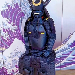 May include: A black samurai armor suit with a horned helmet and a gold crescent moon design. The armor is displayed on a wooden floor in front of a purple and white wave pattern background.
