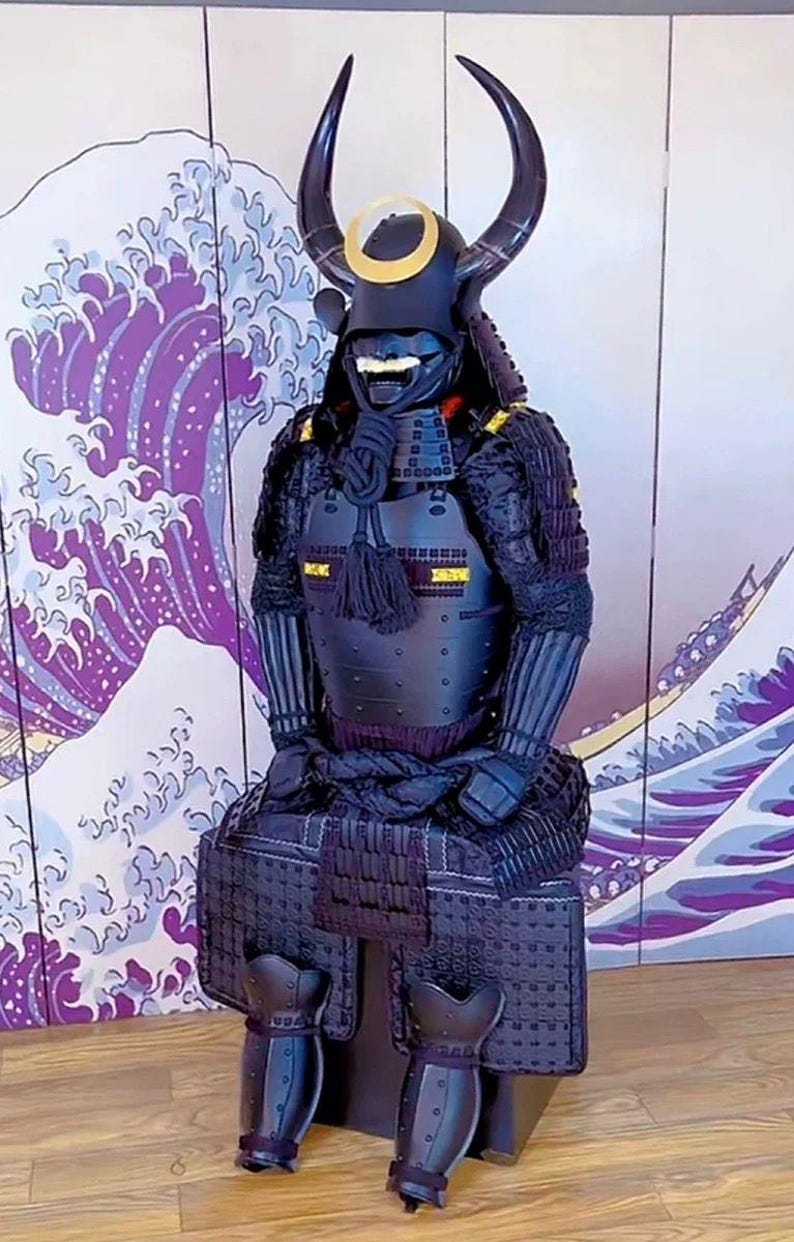 May include: A black samurai armor suit with a horned helmet and a gold crescent moon design. The armor is displayed on a wooden floor in front of a purple and white wave pattern background.