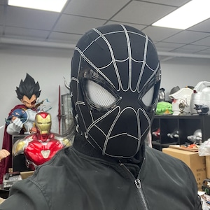 Op de afbeelding: Een zwart-wit Spider-Man-masker met een gaasoogbedekking. Het masker is gemaakt van een zacht, flexibel materiaal en heeft een gedetailleerd ontwerp.