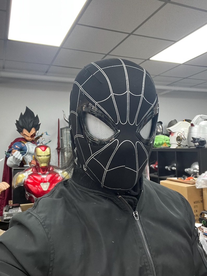 Op de afbeelding: Een zwart-wit Spider-Man-masker met een gaasoogbedekking. Het masker is gemaakt van een zacht, flexibel materiaal en heeft een gedetailleerd ontwerp.