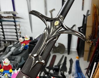 May include: A black and silver sword with a brown leather scabbard. The sword has a decorative hilt with a gold accent. The sword is displayed against a wall with other swords.