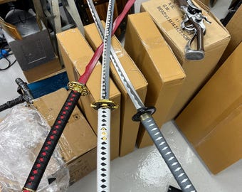 May include: Three katana swords with different handle and blade designs. One has a red handle and blade, another has a white handle, and the third has a gray handle. The blades are silver and have a wavy edge. A decorative pistol is also visible.