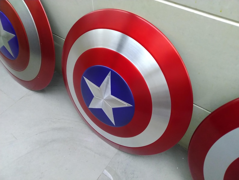 May include: Three Captain America shields, made of metal, with red, white, and blue paint. The shields are round and have a star in the center.