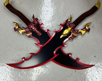 May include: Two crossed fantasy swords with black blades, red trim, and ornate gold and burgundy accents. The handles are wrapped in brown material, and the blades have a curved, serrated design.