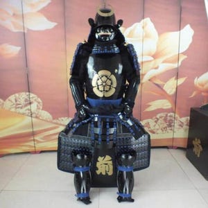 May include: A black samurai armor suit with blue and gold accents. The armor includes a helmet, breastplate, shoulder pads, and leg guards. The armor is decorated with a gold flower design.
