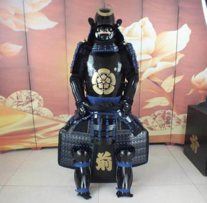 May include: A black samurai armor suit with blue and gold accents. The armor includes a helmet, breastplate, shoulder pads, and leg guards. The armor is decorated with a gold flower design.