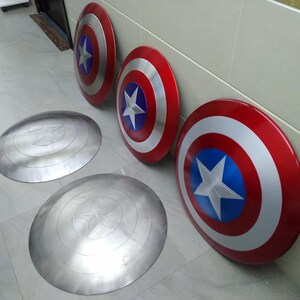 May include: Four Captain America shields, two are painted red, white, and blue, and two are silver with a star design.