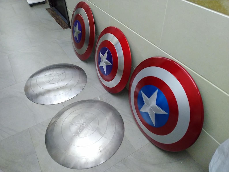 May include: Four Captain America shields, two are painted red, white, and blue, and two are silver with a star design.