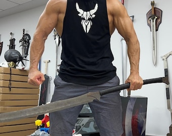 May include: A person holding a large, curved, black-handled sword with a silver blade. The sword is about 5 feet long. The person is wearing a black tank top with a white geometric design on the front. The person is standing in a room with several swords hanging on the wall.
