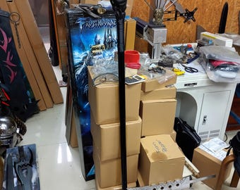 May include: A black staff with a green gem at the top. The staff is surrounded by cardboard boxes and a sword. The staff is about 4 feet long.