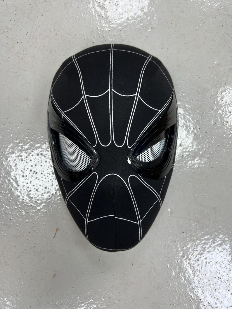 Op de afbeelding: Zwart Spider-Man-masker met een wit spinnenwebontwerp en een zwarte gaasoogbedekking.