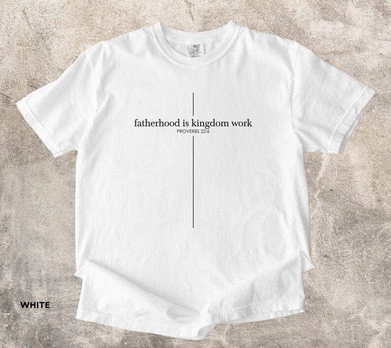 May include: White t-shirt with the text "fatherhood is kingdom work" in black, with a vertical line forming a cross. The text "PROVERBS 22:6" is below the main text. The word "WHITE" is at the bottom left.
