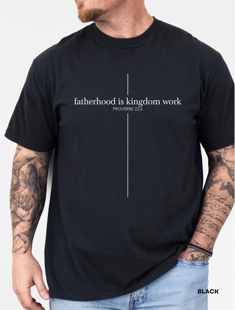 May include: Black t-shirt with the text "fatherhood is kingdom work" and the Bible verse Proverbs 22:6 in white. A vertical white line extends from the text. The word "BLACK" is printed at the bottom right.