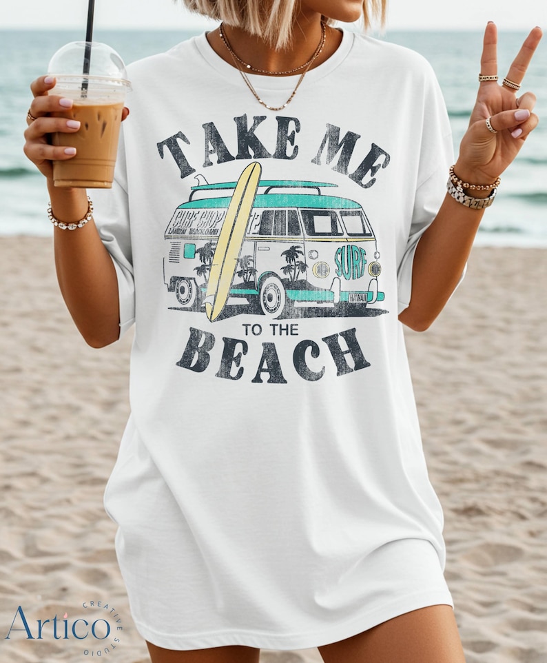 May include: White t-shirt with a graphic of a vintage surf van, a surfboard, and the text "TAKE ME TO THE BEACH" in black. The van is teal and white with palm trees and the word "SURF".
