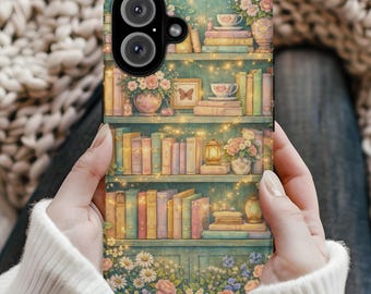 May include: A teal phone case featuring a bookshelf design with books, flowers, and fairy lights. The case has a dual-lens camera cutout and is held by a person wearing a white sweater.