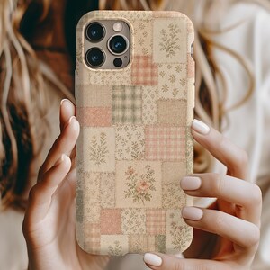 Op de afbeelding: Een beige telefoonhoesje met een patchwork-ontwerp met bloemen- en ruitpatronen in tinten roze, groen en crème. De hoes heeft een matte afwerking en een uitsparing voor de camera.