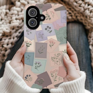 Puede incluir: Una funda para teléfono con un patrón floral. La funda está hecha de plástico duro y tiene una parte posterior transparente. El patrón floral está en tonos de rosa, morado y verde. La funda tiene un recorte para el objetivo de la cámara.
