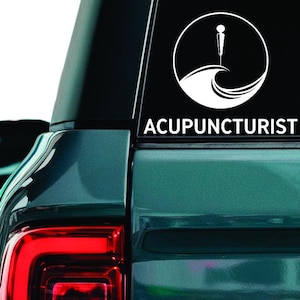 May include: White vinyl sticker showing a circular design with an acupuncture needle over a wave, and the word "ACUPUNCTURIST" underneath. The sticker is on the rear window of a teal car.