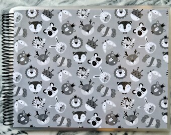 May include: A gray and white patterned scrapbook cover with a variety of animal faces, including lions, tigers, deer, and rabbits.