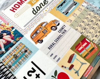May include: A white and red spiral bound notebook with a colorful design featuring a school bus, a typewriter, a red apple, and the text "Homework is done".