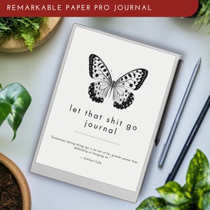 May include: A white e-reader with a black and white butterfly illustration and the text "let that shit go journal" on the screen. The text below the butterfly reads "Sometimes letting things go is an act of far greater power than defending or hanging on." - Eckhart Tolle.