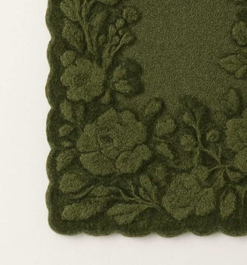May include: A close-up of a dark green, square-shaped decorative mat with a scalloped edge. The mat features an embossed floral design, including roses and leaves. The design is a darker shade of green than the background.