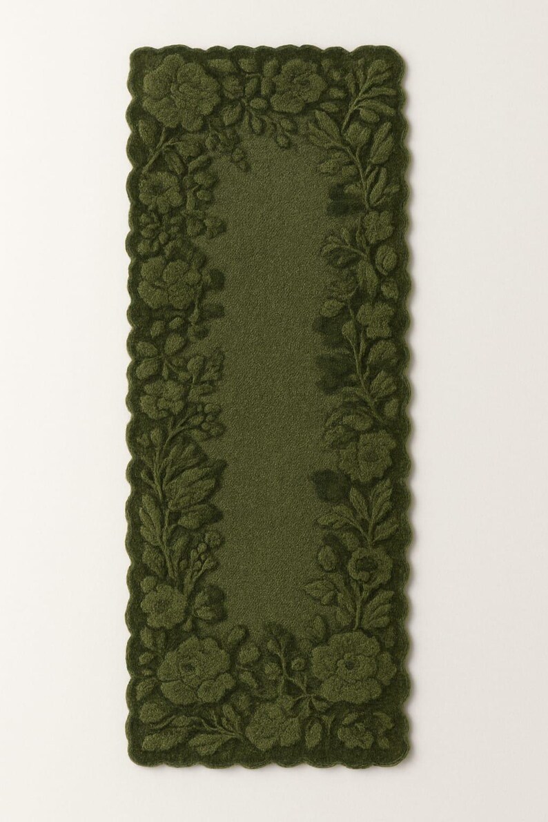 May include: Olive green rectangular rug with a floral design. The rug features a central olive green field framed by a border of embossed flowers and leaves. The edges have a scalloped trim.