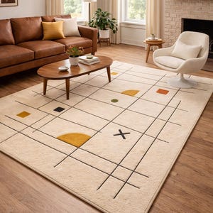 May include: Beige area rug with a geometric design. The rug features a grid pattern with black lines and colorful shapes, including yellow, orange, and green. The rug is placed in a living room setting with a brown leather sofa and a white chair.