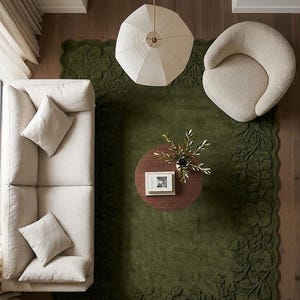 May include: Overhead view of a living room with a green floral rug, a cream-colored sofa with pillows, and a round wooden coffee table. A cream-colored armchair and a geometric pendant light are also visible.