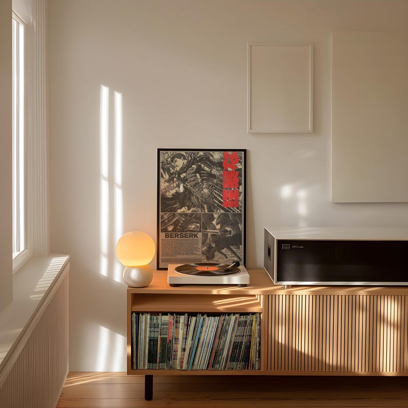 K&ouml;nnte beinhalten: Ein Holzschrank mit einer Sammlung von Schallplatten, einem Plattenspieler und einem gerahmten "Berserk"-Poster. Eine kugelf&ouml;rmige Lampe und eine schwarz-wei&szlig;e Audiokomponente befinden sich auf dem Schrank. Der Raum wird von nat&uuml;rlichem Licht beleuchtet.