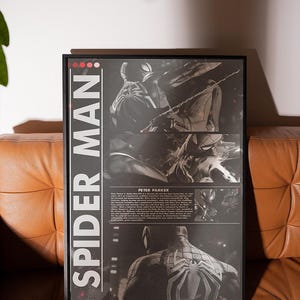 Op de afbeelding: Ingelijste Spider-Man-poster met meerdere afbeeldingen van de superheld in actieposes. De poster heeft de woorden "SPIDER MAN" in witte tekst op een zwarte achtergrond. De poster wordt weergegeven op een bruine leren bank.