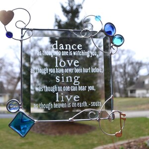 May include: A glass framed quote with a silver metal frame and blue and gold accents. The quote reads: "dance as though no one is watching you, love as though you have never been hurt before, sing as though no one can hear you, live as though heaven is on earth. -souza"