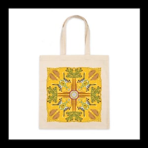 May include: Cream-colored tote bag with a square design featuring a yellow background. The design includes a central circular emblem, birds, and plant-like shapes. The bag has a simple, rectangular shape with two handles.