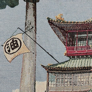 May include: A tapestry depicting a traditional Chinese building with a red roof and a tall chimney with smoke coming out of it. The building has a white flag with black Chinese characters on it. The tapestry is made of a woven fabric with a textured surface.