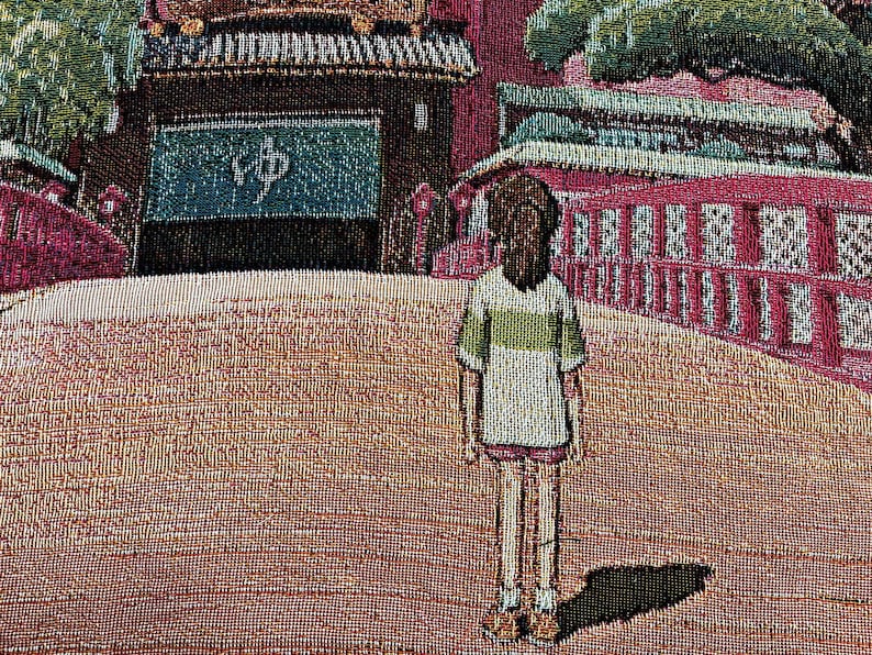May include: A tapestry depicting a young person standing in front of a red and green building with a sign that reads "ゆめ". The building has many windows and a roof with a green overhang. The person is wearing a white shirt with a green stripe and a green skirt.