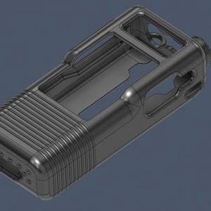 May include: A dark gray, rectangular device with a ridged front and a hollowed-out interior. The top features a rectangular opening with rounded edges and a handle-like structure. The device has a cylindrical component on one end and multiple small holes.