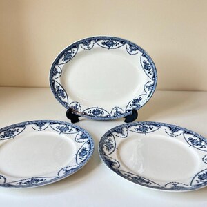 May include: Three white oval serving platters with a blue floral border. One platter is displayed on a black stand. The platters have a classic, elegant design, suitable for serving food.