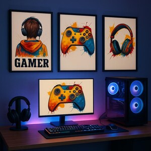 Op de afbeelding: Een gaming setup met ingelijste prints van controllers en koptelefoons, een monitor met een controller afbeelding, een toetsenbord, muis en een computertoren met verlichte ventilatoren. Het woord "GAMER" staat op een van de prints.