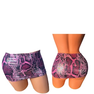 Könnte beinhalten: Zwei Mini-Röcke mit einem rosa-schwarzen Schlangenmuster. Die Röcke werden auf Schaufensterpuppen gezeigt, einer von der Seite und einer von hinten. Der Stoff hat ein glänzendes, metallisches Finish.