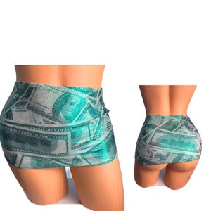 May include: A short, green and gray skirt with a money print design. The skirt is made of a stretchy, shiny fabric.
