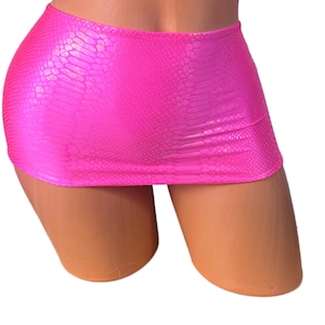 May include: A vibrant pink mini skirt featuring a snakeskin texture. The skirt is crafted from a shiny material and is designed to be high-waisted. The garment is displayed on a mannequin.