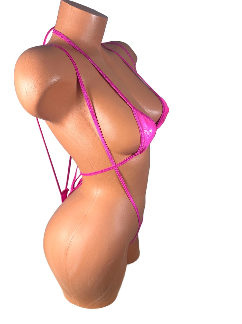 May include: A hot pink, string bikini with a textured pattern. The bikini top has triangle cups and ties around the neck and back. The bottom is a thong style with side ties. The swimsuit is displayed on a mannequin.