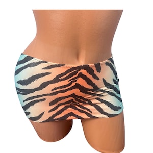 May include: A low-rise mini skirt featuring a vibrant tiger stripe pattern. The fabric displays a gradient color transition, shifting from a soft light blue at the sides to a warm orange hue in the center, overlaid with bold black stripes.